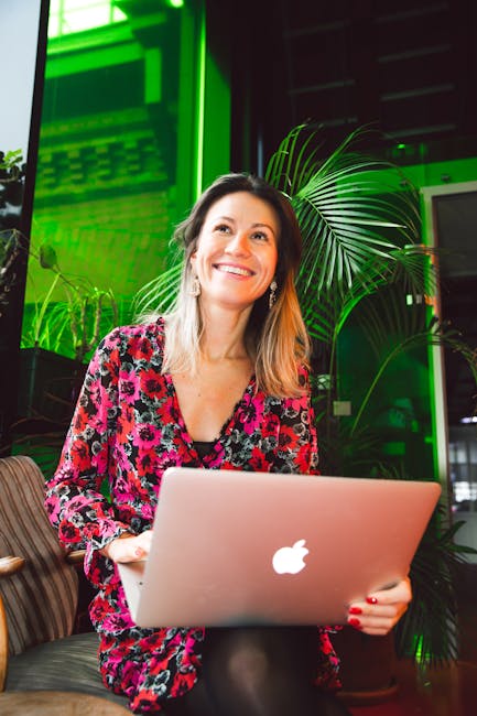 Smiling woman holding a laptop, confident after receiving in-home Computer Training.