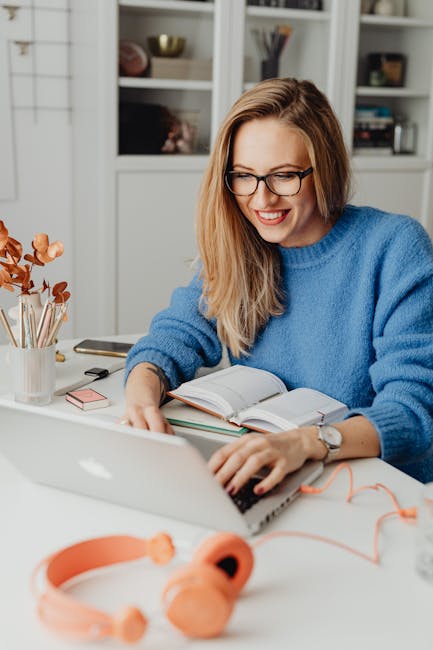 Smiling woman seated at a table working on her laptop during an in-home computer support session.