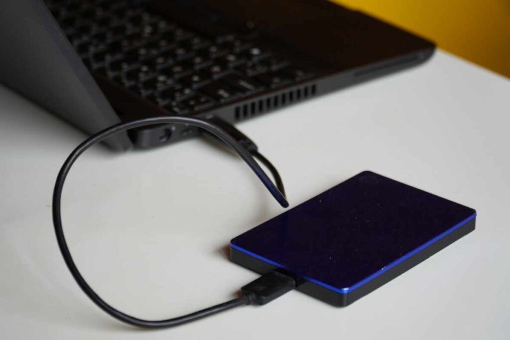 A Windows laptop connected to an external hard drive, representing a complete Windows backup setup for protecting files and system data.
